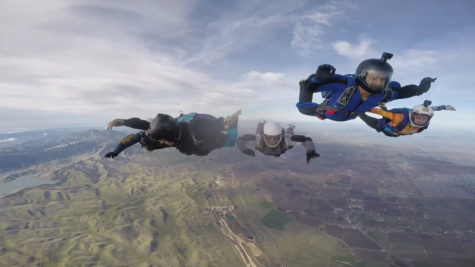 Skydivers in freefall above a mountainous landscape