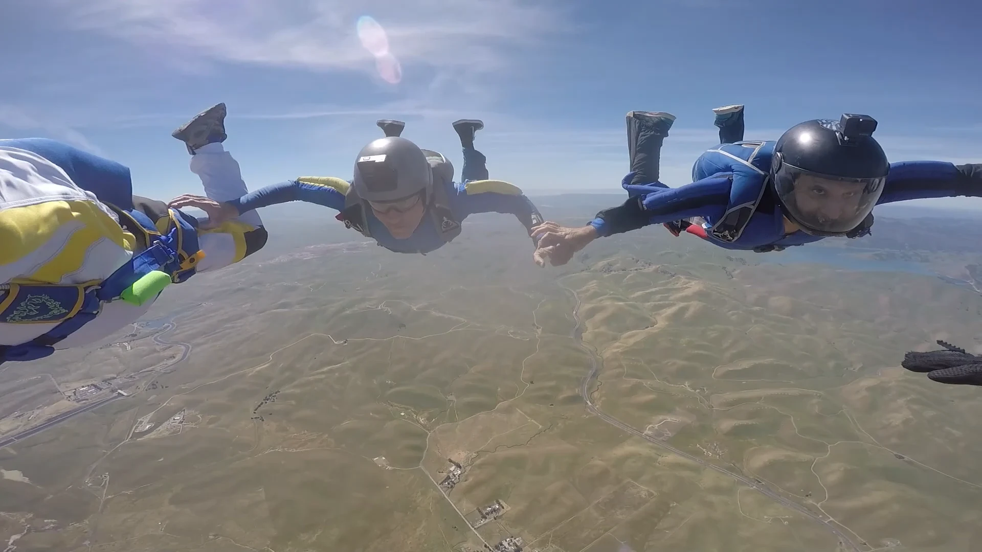 Skydivers in freefall above a mountainous landscape