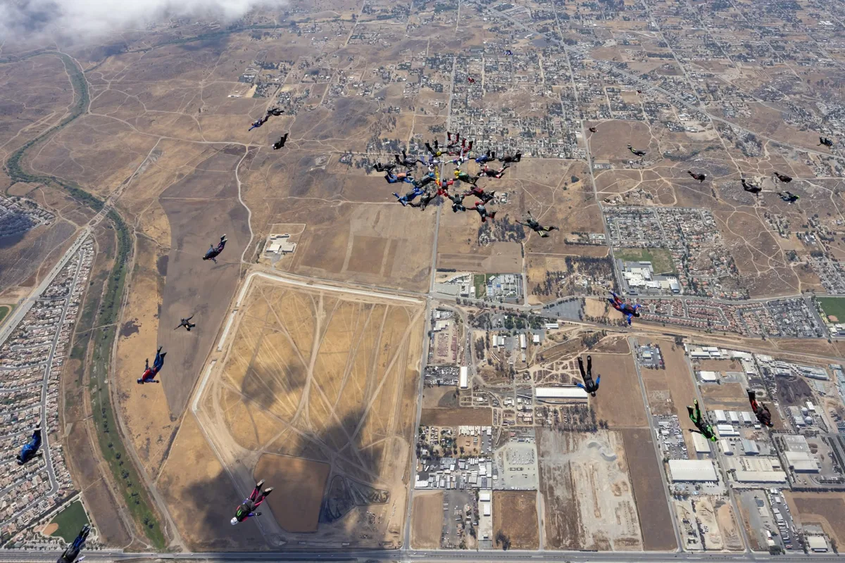 Skydivers in formation above the desert landscape