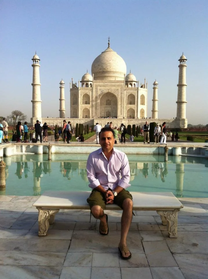 Umar Rafi seated on a marble bench before the Taj Mahal in Agra